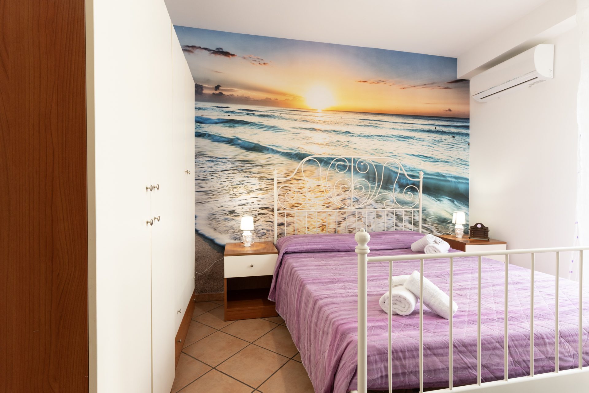 Camera da letto di Allejanni con murale del tramonto sul mare
